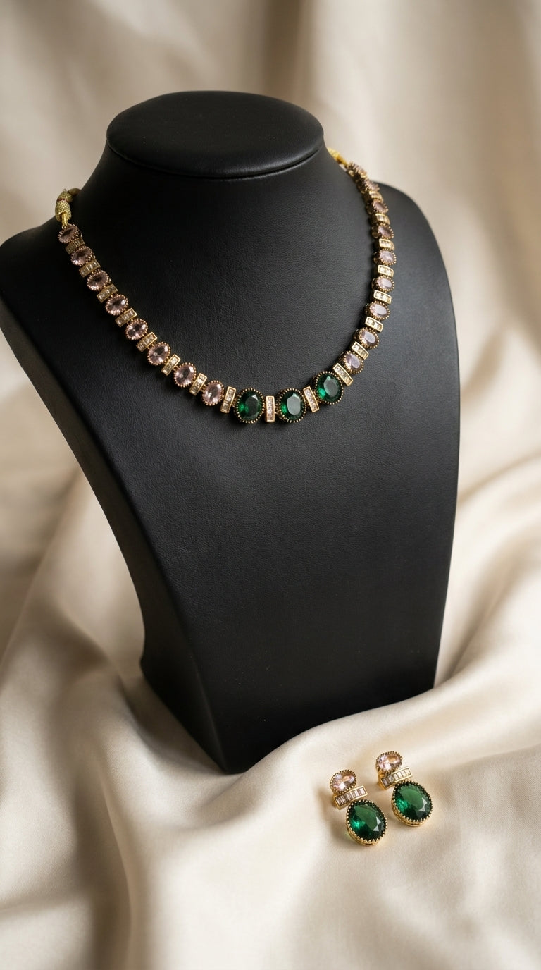 Gold-tone jewellery set with emerald green and pink stones, necklace on black display bust with matching earrings — view 3