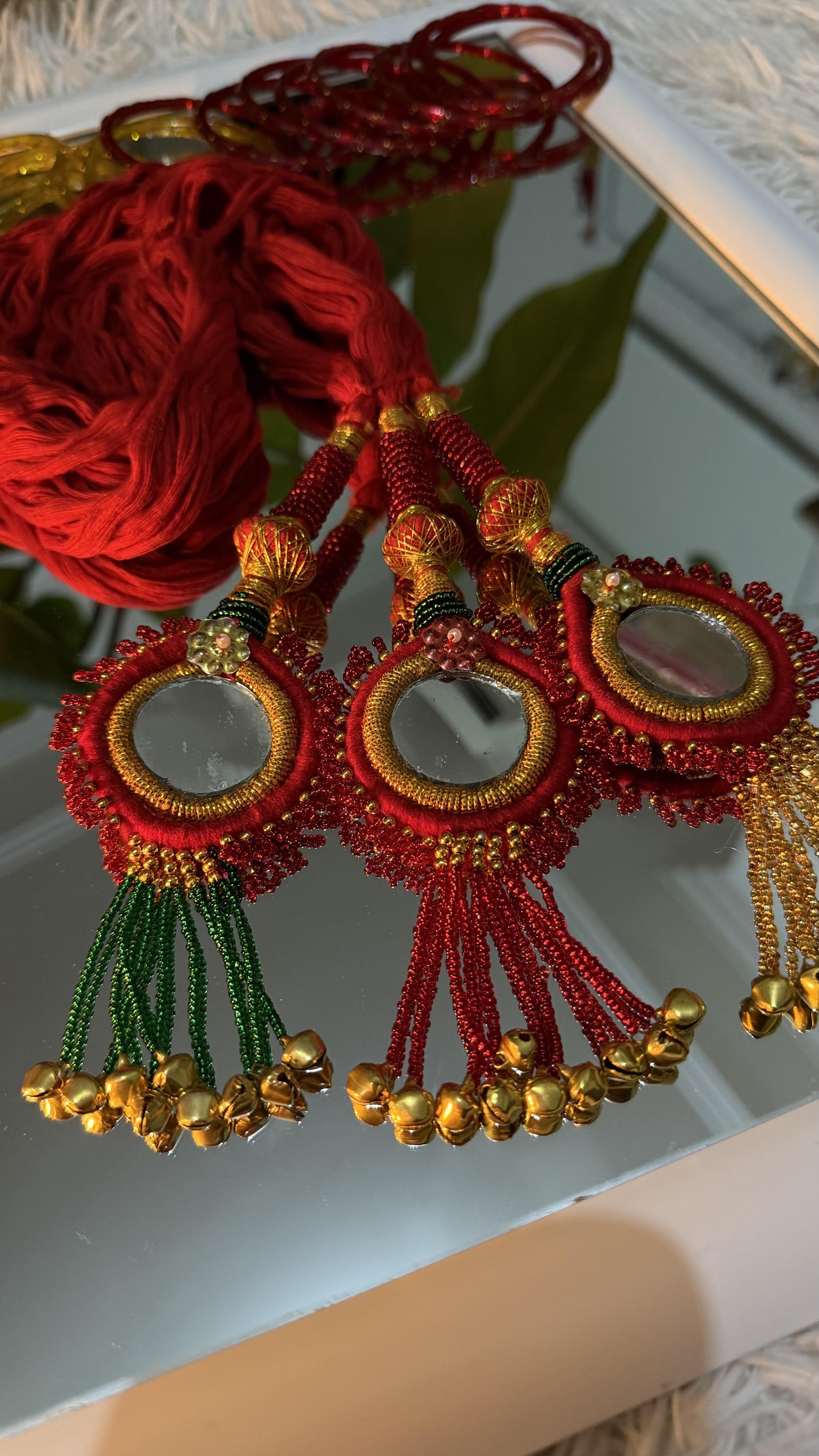 Red handcrafted Lachha Dori with circular mirror medallions, gold zari wrapping, seed bead tassels and ghungroo bells —