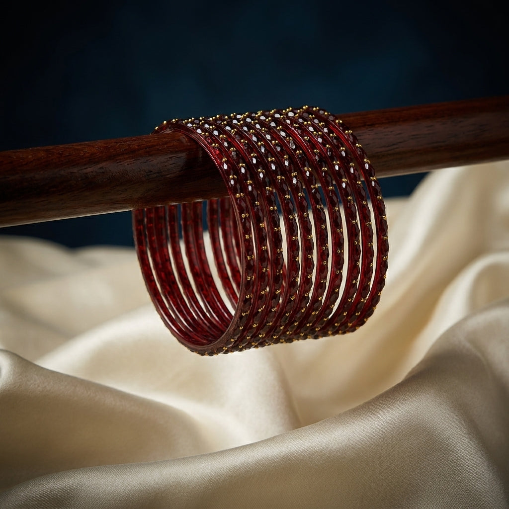 Set of 12 deep crimson red bangles with gold bead detailing stacked on a wooden display rod — Behuli Australia — view 2