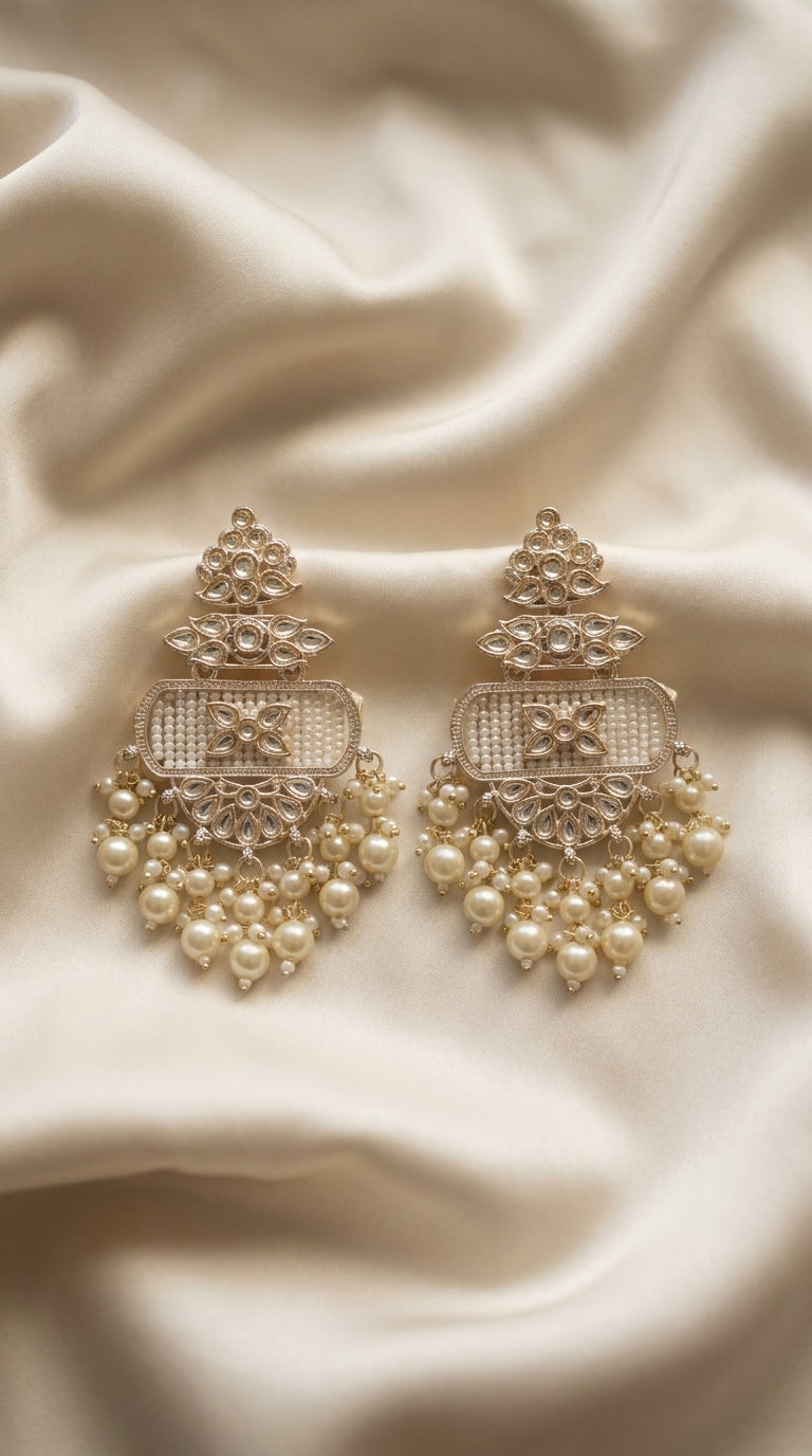 Ivory and gold-tone kundan-style drop earrings with seed bead panel and cascading pearl clusters on cream silk — Behuli
