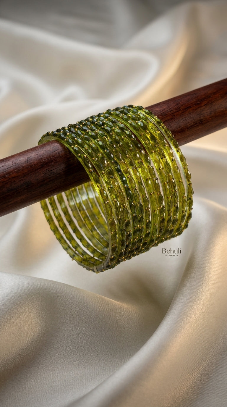 Olive green beaded bangles set of 12 with gold-toned accents displayed on a wooden rod