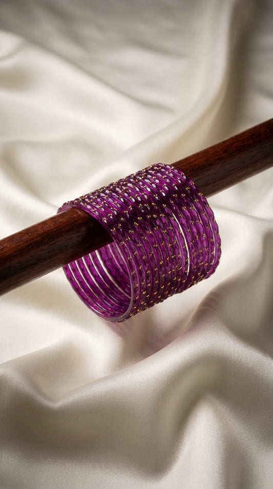 Deep purple 12-piece glass bangles with gold dot detailing displayed on a wooden rod — Behuli Australia