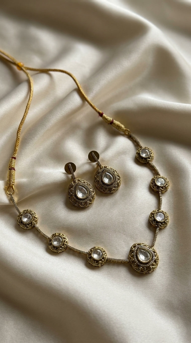 Antique gold-tone kundan-style necklace and earring set with clear stone centrepieces on a black jewellery bust — Behuli — view 2