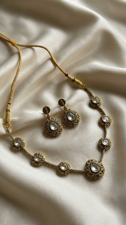 Antique gold-tone kundan-style necklace and earring set with clear stone centrepieces on a black jewellery bust — Behuli — view 2