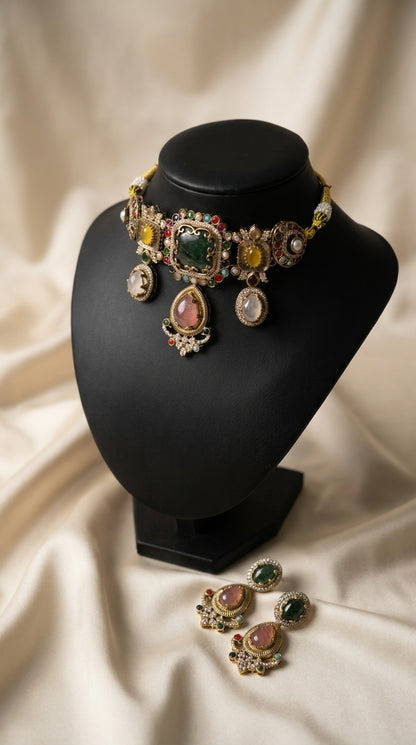 Antique gold jewellery set with green, pink and yellow stones, pearl detailing and matching statement earrings on black