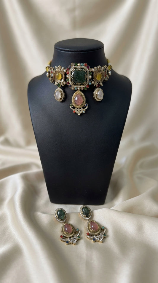 Antique gold jewellery set with green, pink and yellow stones, pearl detailing and matching statement earrings on black — view 2