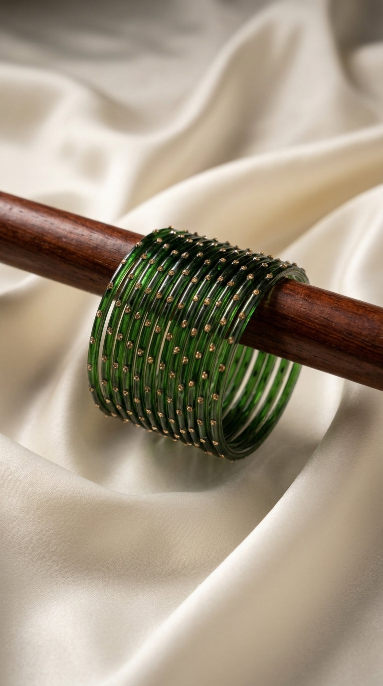 Set of 12 deep forest-green bangles with gold-tone dot embellishments displayed on a wooden rod — Behuli Australia