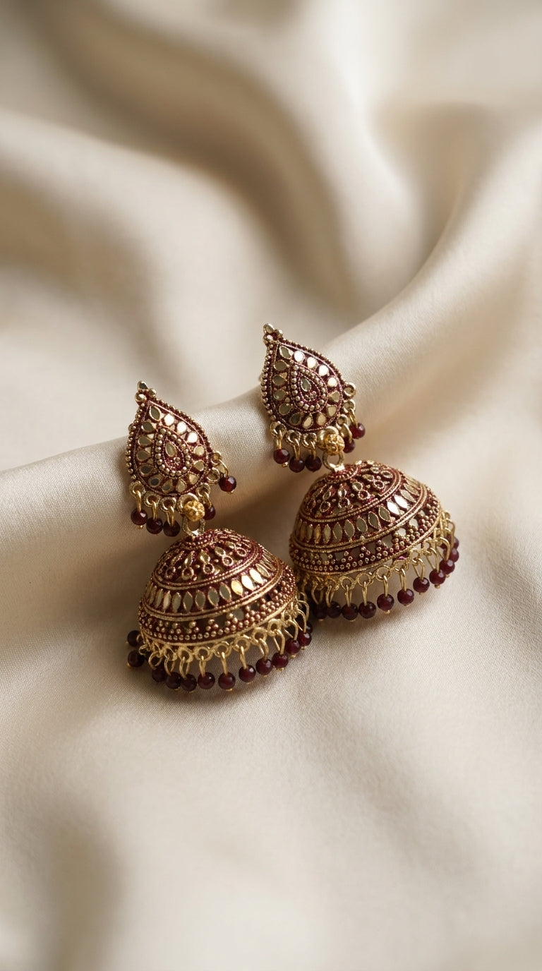Maroon and antique gold jhumka earrings with mirror embellishment, dome bell silhouette and deep red bead fringing — Behuli
