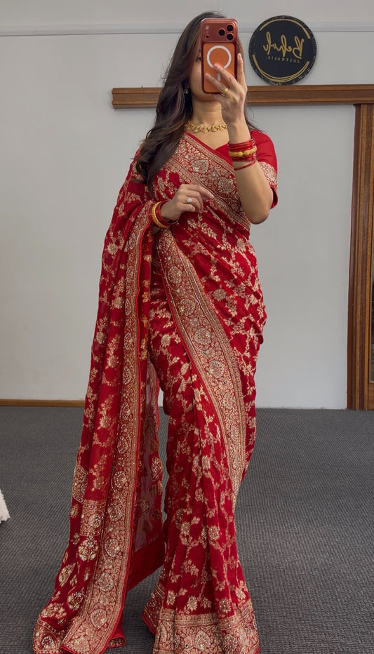 Red khaddi georgette saree with gold zari embroidery and floral border design worn with matching red blouse