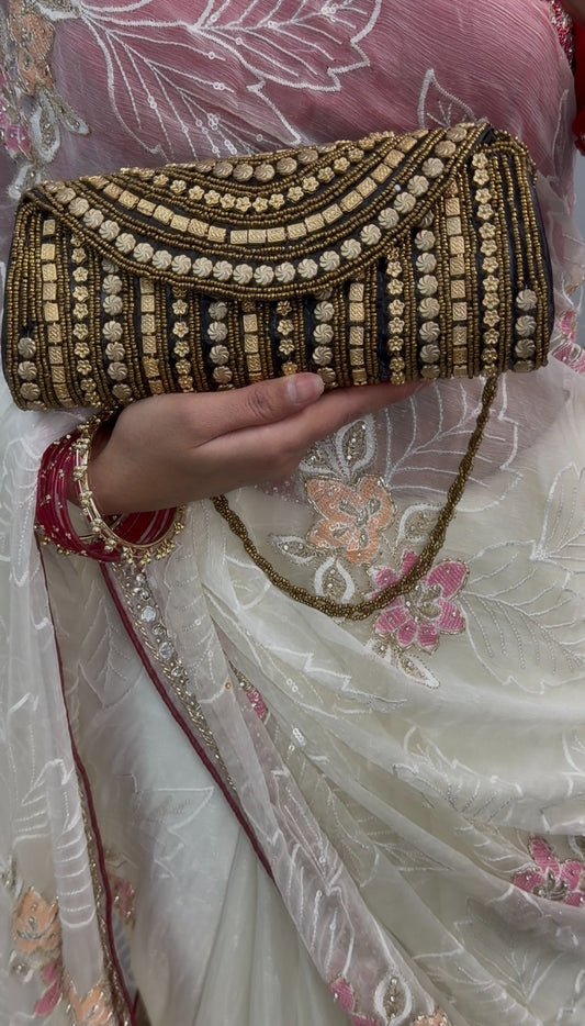 Black clutch bag with gold beadwork and sequin detailing, featuring a beaded chain strap, displayed on wooden table — view 2
