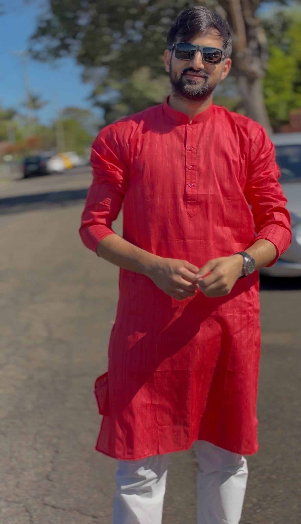 Man wearing a red mandarin collar kurti with subtle woven texture and white trousers, standing outdoors