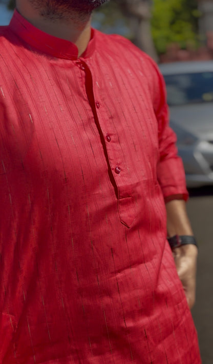Man wearing a red mandarin collar kurti with subtle woven texture and white trousers, standing outdoors — view 2