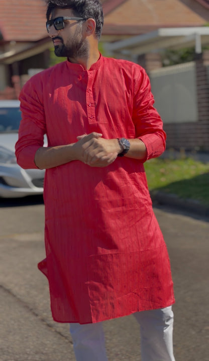 Man wearing a red mandarin collar kurti with subtle woven texture and white trousers, standing outdoors — view 4