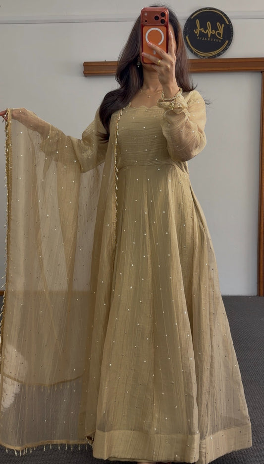 Golden beige Anarkali with scattered sequin detailing, scalloped neckline and sheer beaded dupatta draped to the side
