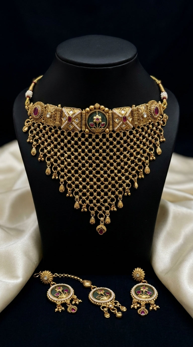 Antique gold-tone choker jewellery set with jali lattice necklace, maang tikka and round earrings featuring green and ruby
