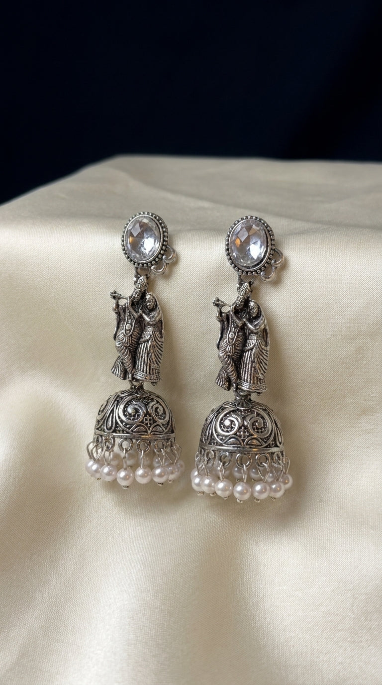 Oxidised silver Radha Krishna jhumka earrings with filigree dome bell and white pearl drops on ivory fabric — Behuli — view 2