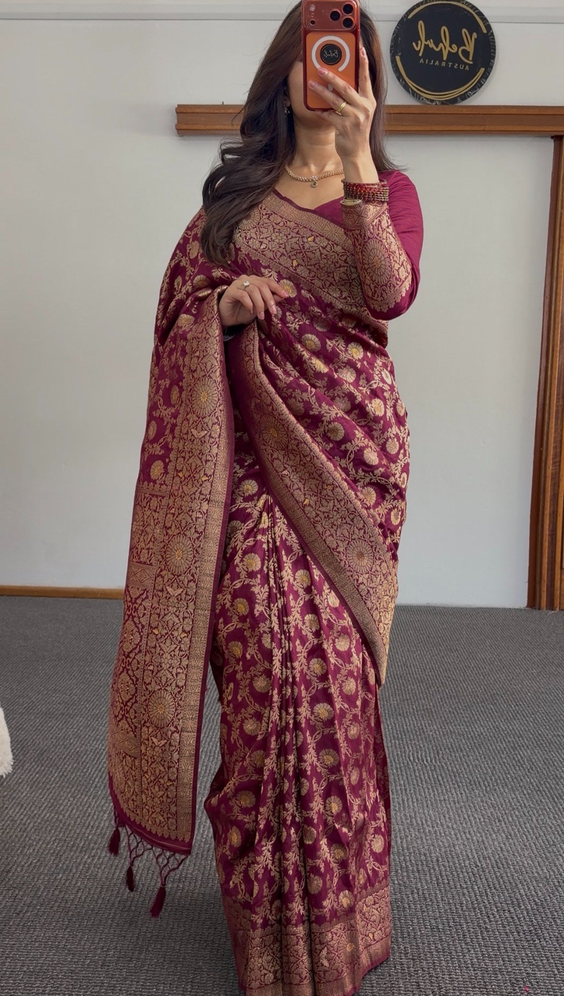 Maroon saree with gold zari floral weave, pallu draped over shoulder, worn with matching maroon blouse